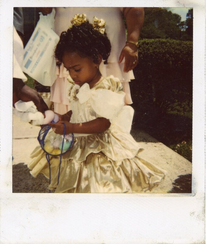 Scan of a color photograph of Sierra King. Sierra in gold dress standing by Mamarita holding basket with eggs.