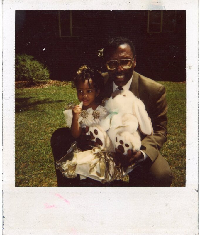 Scan of a color photograph of Sierra King. Sierra King in gold dress sitting on Walt Stephens lap while she holds a piece of candy and looks away from the camera. Walt is also holding white stuffed in the lawn of Hoosier Memorial United Methodist Church  