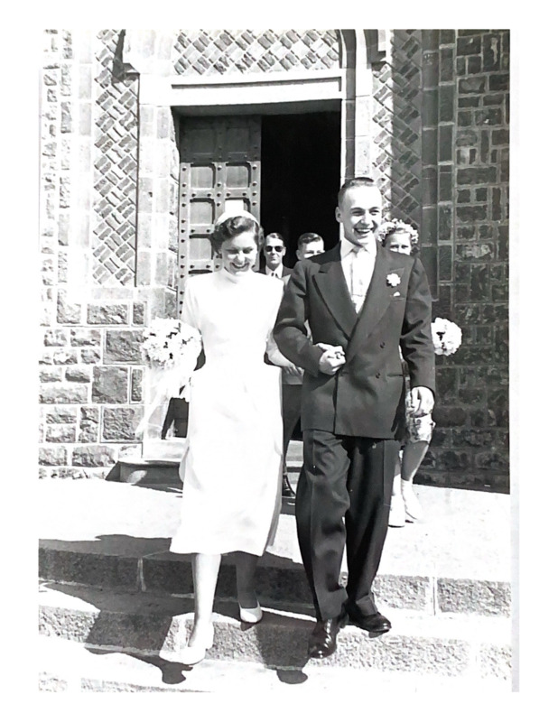 Scan of a black and white photograph of John and Jackie Turpin on their wedding day in Asmara, Eritrea outside of the chapel where the ceremony took place. Jackie's father can be seen in the background. 