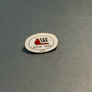 image of a white oval enamel lapel pin with a red and blue logo. "Active West 200" inlaid in gold metal.