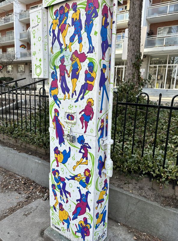 White electrical box painted white featuring groups of multicoloured people doing various activities