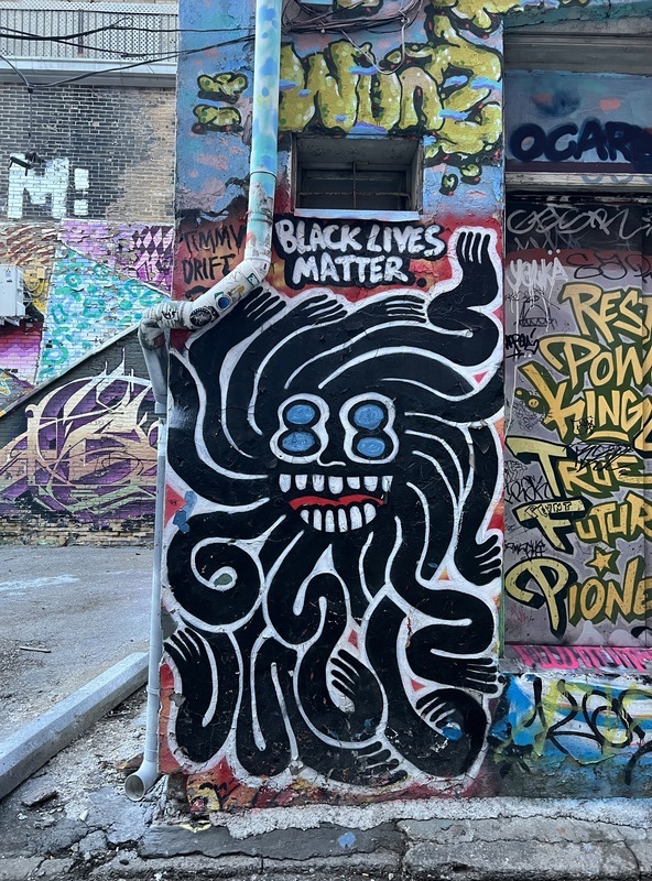 A tentacled creature in black with the words "Black Lives Matter" written in black 