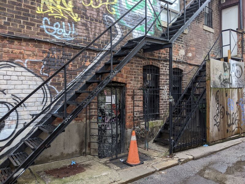 Tags surrounding stairs in an alley.