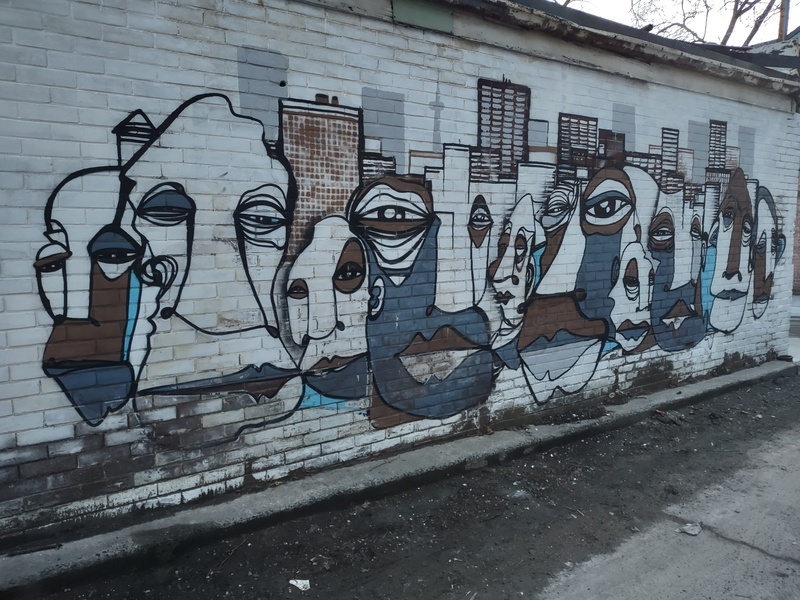 Painted mural of faces in front of the Toronto skyline