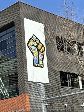 A painted raised fist, collaged with varying symbols of social and cultural identities