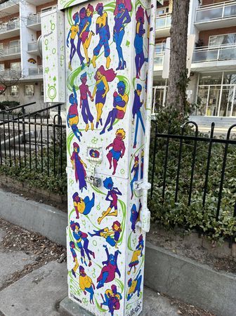 White electrical box painted white featuring groups of multicoloured people doing various activities