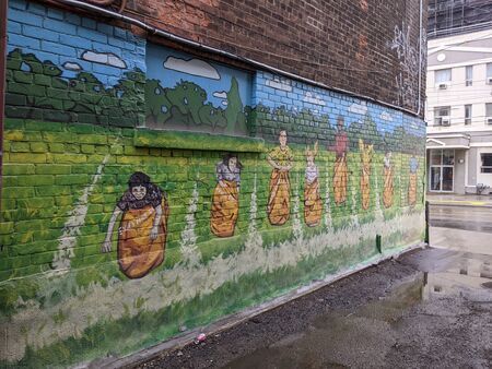 Mural of kids in a potato sack race on a brick wall in a back alley.
